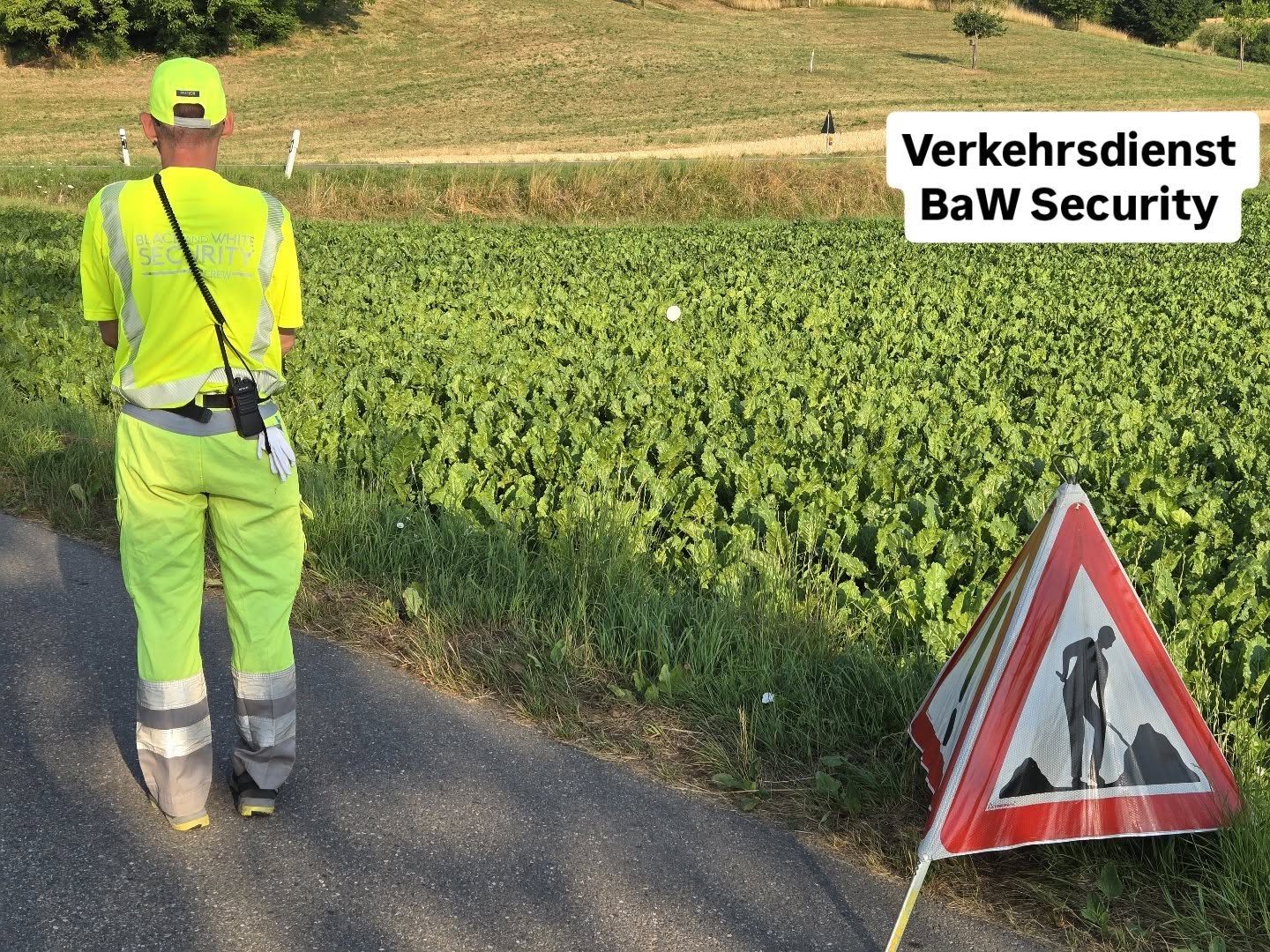 Verkehrsdienstmitarbeiter mit Warnschild bei einer Baustelle